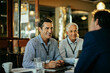 © Marko Geber - Diverse group of businessmen having a meeting in a cafe and discussing business