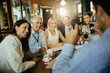 © Marko Geber - Group of business people having a meeting and taking a photo with a smart phone in a cafe bar