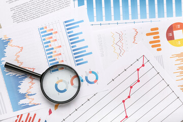Fototapete - Magnifier with many business graphics and diagrams as background, closeup