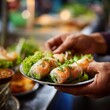 © Premium Resource - a vendor's hands preparing fresh Vietnamese spring rolls, translucent rice paper filled with shrimp and herbs, at a bustling street market, motion and authenticity