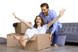 © ty - Happy couple is having fun with cardboard boxes in new house at moving day, woman riding sitting in cardboard box while man pushing it on a transparent background
