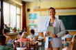 © Drazen - Happy African American female teacher in classroom looking at camera.