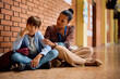 © Drazen - African American teacher talking to sad elementary student in hallway at school.