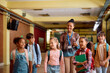 © Drazen - Happy black teacher and her elementary students walking through school hallway.