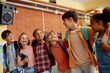 © Drazen - Group of happy diverse school kids standing embraced in hallway.