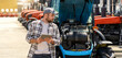© Barillo_Images - Technician performing tractor engine inspection in outdoor farm machinery lot