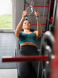 © VictorCanalesStudio - Smiling woman lifting weights on a cable row machine, strengthening her back muscles