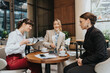 © qunica.com - Three women discussing ideas while enjoying coffee together in an elegant cafe.
