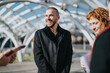 © qunica.com - A group of professionals enjoying a cheerful conversation in an urban outdoor setting. Their positive interaction conveys teamwork and camaraderie.