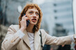 © qunica.com - A woman dressed in professional attire engages in conversation on a smart phone, conveying determination and purpose in a city environment against blurred background.