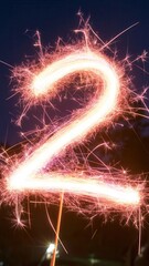 Poster - Number two created by light painting with bright pink and white sparkles on dark background with reflections