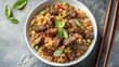 © somsri - Minimalist presentation of beef fried rice in a white bowl on a gray stone background with chopsticks