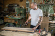 © Zoran Jesic - Carpenter working wood plank using clamps in workshop