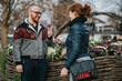 © qunica.com - A man offers a floral gift to a smiling woman in an urban garden setting, showing friendship.