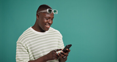 Phone, smile and black man in studio for social media, text message or reading fashion blog. Mobile, online chat and happy model on digital app for news, check forum and space at green background