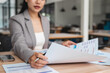 © jojo - Businesswoman checking documents on stacked desk