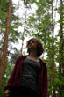 © Anastasia.photoyoga - Beauty face young woman looking up on a green pine trees in the forest on sun spring weather. Girl walking in woods, eyes look above in fashion clothes and breath fresh air. Closeup emotion portrait