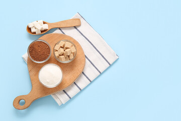 Wall Mural - Bowls and spoon with different types of sugar on blue background