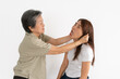 © Suthida - Fuuny Asian Thai senior woman squeezing young woman's ears, scolding isolated over white wall.