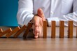 © Md Fazly Rabby - Hand Stopping the domino business crisis effect or risk protection concept, business solution and intervention