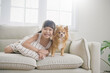 © paulaphoto - Portrait of little asian girl stay home sit on the sofa  living room with lovely dog. Happy moment of pure love toddler playing with little dog, minimal happy pet animal lifestyle concept