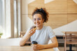 © Dusan Petkovic - Portrait of cheerful hungry girl sitting in fast food restaurant with coffee to go and doughnut in hands and smiling at the camera.