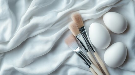 Poster - Elegant makeup brushes alongside pristine white eggs on soft fabric, representing beauty, simplicity, and creativity in a serene and artistic setup for beauty enthusiasts.