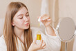 © st.kolesnikov - Young Woman Applying Facial Oil Serum with Dropper for Skin and Hair Care Beauty Routine at Home