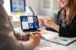 © Apichat - A woman is smiling and pointing at a tablet with a graph on it