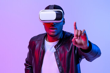 Aufkleber - Excited Young African American Guy In VR Glasses And Leather Jacket Enjoying Virtual Reality Experience, Amazed Black Gamer Man Standing In Neon Lighting Over Purple Studio Background, Copy Space