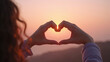© Jari.art - Person forms heart shape with their hands against beautiful sunset, symbolizing love and connection. warm colors of sky create serene atmosphere