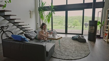 millennial woman working from home in her pajamas in the light and spacious living room. Remote jobs and digital nomad concept