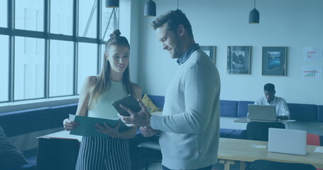 Poster - Two colleagues discussing documents and tablet in office lounge, with wooden tables