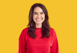 © Studio Romantic - People and sincere emotions concept. Positive brunette woman with toothy smile wears casual red jumper, posing against vivid yellow background, expressing happiness, being in good mood