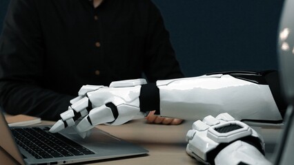 Poster - A close-up view of a futuristic robotic arm reaching for a laptop, reflecting innovations in technology, human-like design, and the future of artificial intelligence in the workspace.Noogenesis
