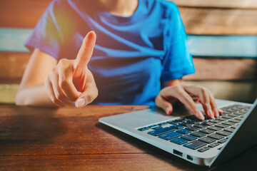 Poster - Woman using laptop. Close-up of a Person's Hand Gesture While Using a Laptop in a Cozy Wooden Environment