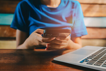 Poster - Woman using laptop. Close-Up of Person Using Smartphone While Sitting at Desk with Laptop in Modern Indoor Setting