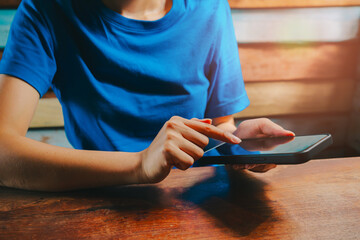 Poster - Woman using smartphone. Person using tablet device in a casual setting with wooden background and bright lighting for lifestyle and technology themes
