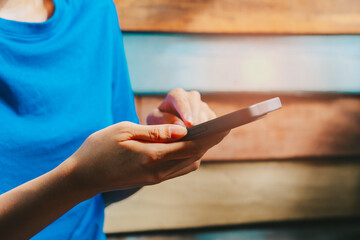 Poster - Woman using smartphone. Person using smartphone for communication against colorful wooden backdrop with natural light in modern lifestyle setting