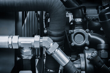 Poster - Blue tone engine with a black hose attached to it. The hose is connected to a black pipe