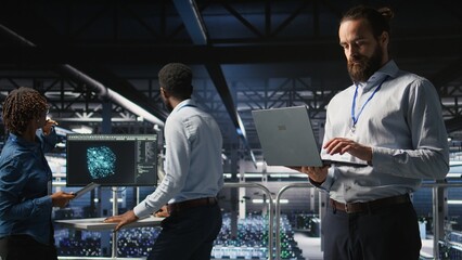 Poster - Computer scientists on data center industrial platform analyzing performance outputs on laptop. Server farm IT experts collaborating on finetuning rigs configurations,