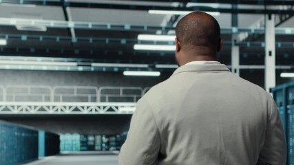 Poster - Technician walking in data center workplace with multiple rows of fully operational mainframes. Worker overseeing server farm built for storage enterprise solutions systems, camera B