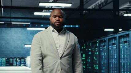Poster - Employee walking in data center with blinking lights on rigs showing system activity. IT professional overseeing dimly lit server farm with equipment arranged for smooth operations, camera B