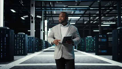 Poster - IT professional looking over data center checkup checklist paperwork on tablet. African american man walking in server farm, reading documentation files on device, camera A