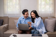 © Apichat - A man and woman are sitting on a couch looking at a laptop