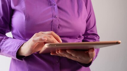 Poster - Close-up of a woman's hands holding a tablet, wearing a purple shirt with buttons on the front and standing against a white background.