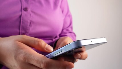 Poster - Close-up of a woman's hand holding a smartphone and typing on it. She is wearing a purple shirt against a white background.