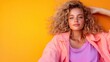 © svastix - A fashionable young woman poses confidently against a vibrant yellow backdrop, showcasing her curly hairstyle and relaxed vibe in this portrait capturing modern youth culture.