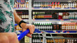 © Stockah - Close-up of a shopper's hands with a shopping trolley walking along alcohol drinks aisle