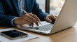 © Khamdani - Focused Professional: Laptop, Pen, and Smartphone on Desk